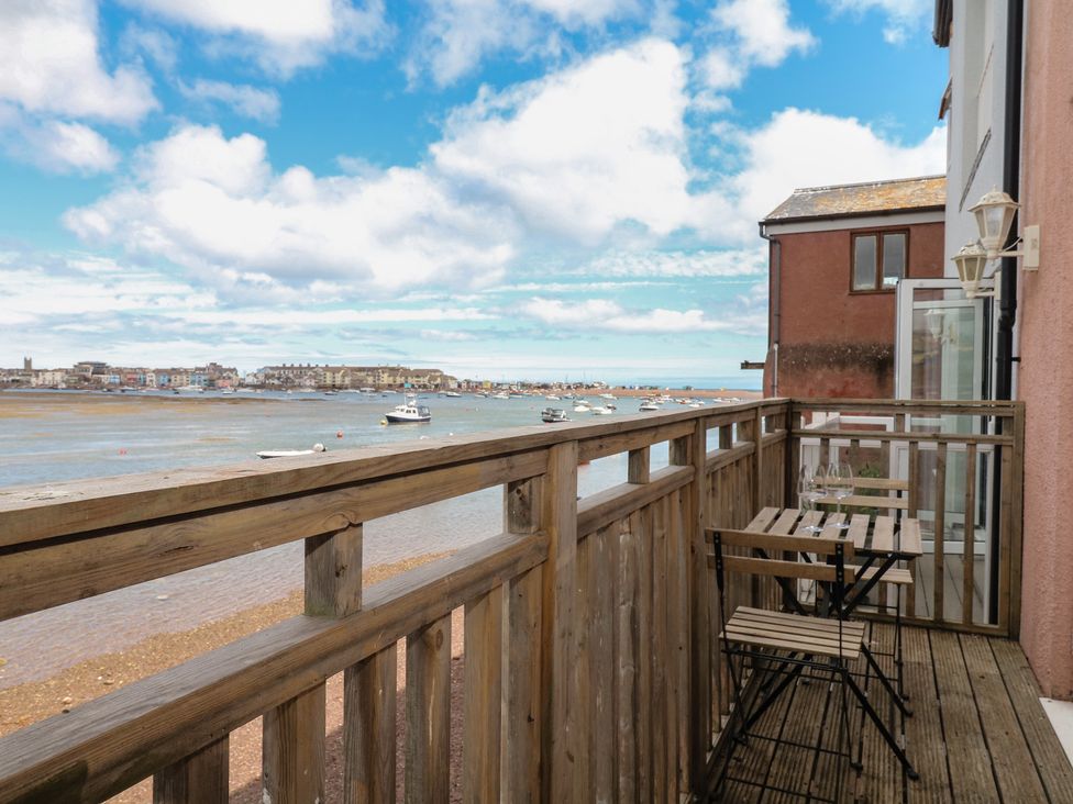 A balcony with wooden table and chairs overlooking the ocean at The Dolphins in Shaldon