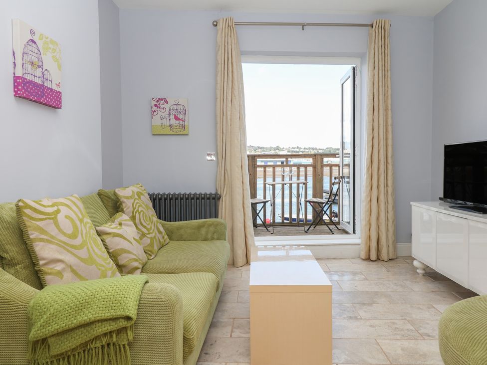 A living room with a sofa and a television at The Dolphins in Shaldon
