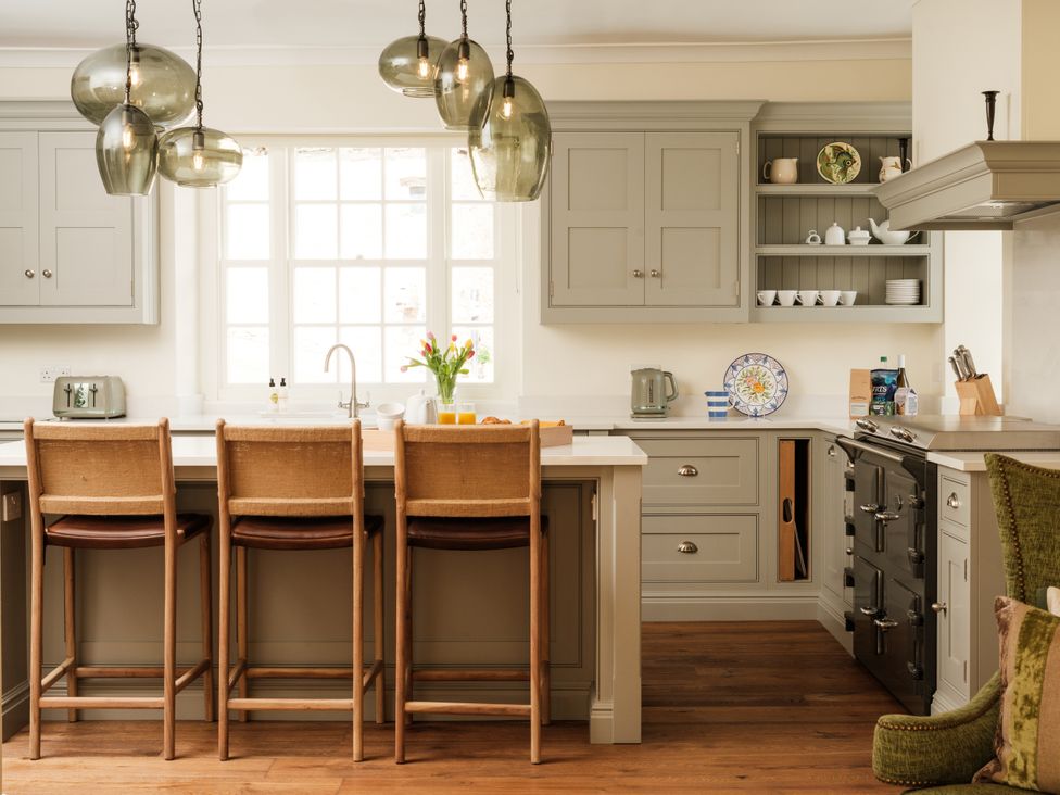 A kitchen with bar stools and cabinets at Sandridge Barton Stoke Gabriel