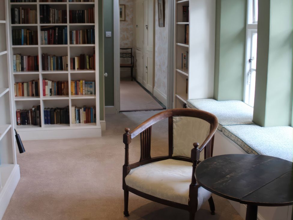 A reading room with a bookshelf and chair at Wootton House Butleigh Wootton, near Compton Dundon