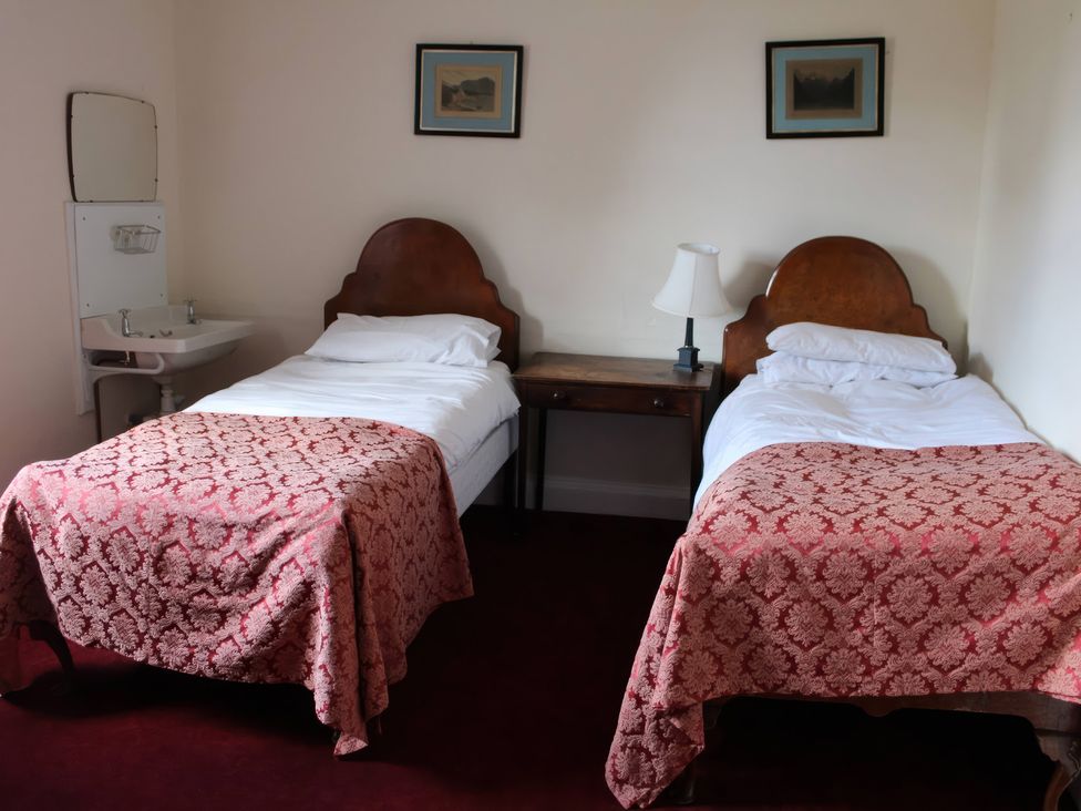 A bedroom with twin beds, a wash basin, and a lamp at Wootton House, Butleigh Wootton, near Compton Dundon