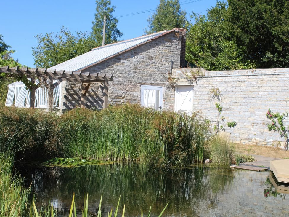 A garden with a pond and a stone building at Wootton House in Butleigh Wootton, near Compton Dundon