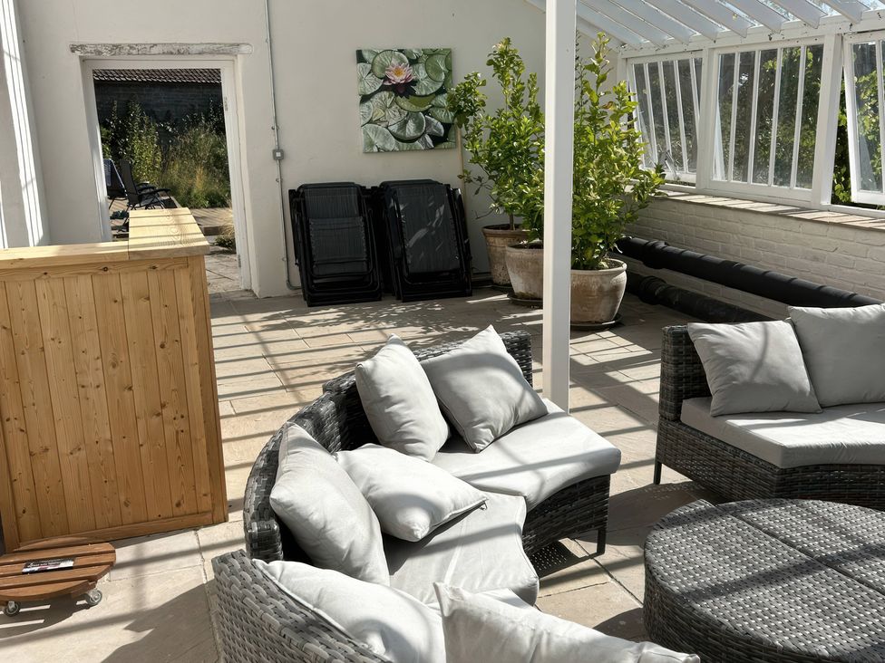 A conservatory with seating and plants at Wootton House Butleigh Wootton near Compton Dundon