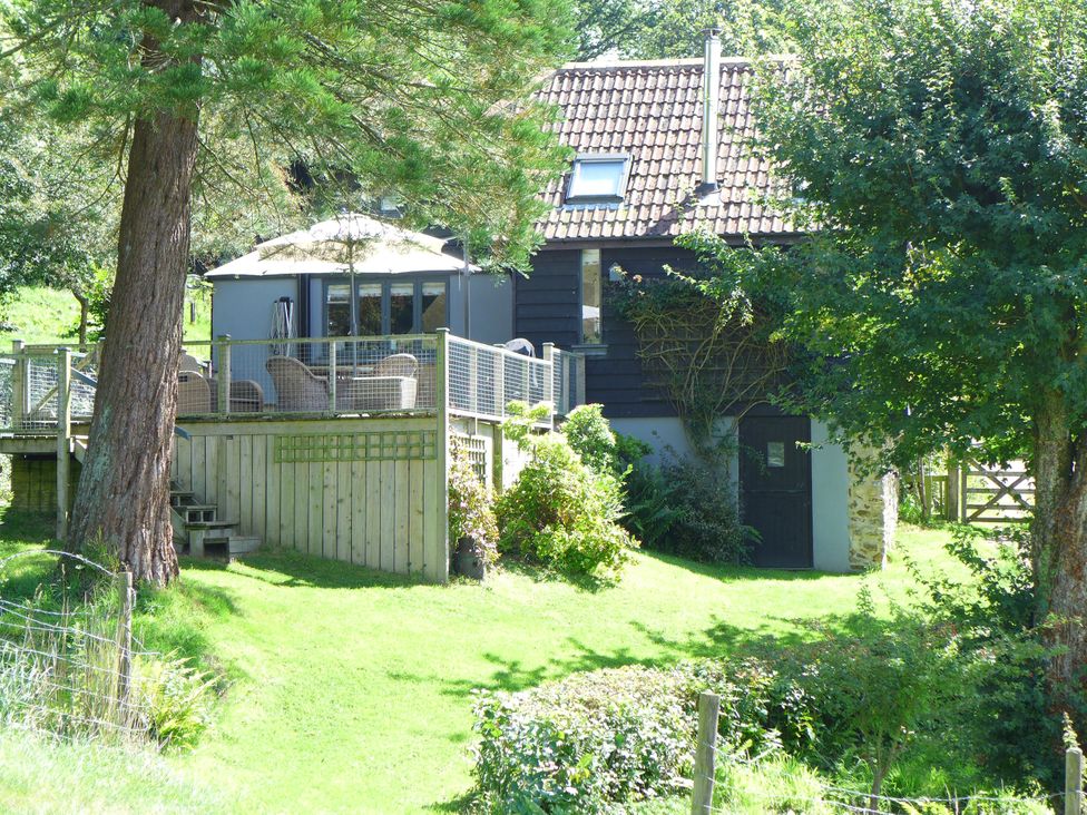 An outdoor view of a house with a deck and seating at Little Evanses, Dalwood, near Axminster