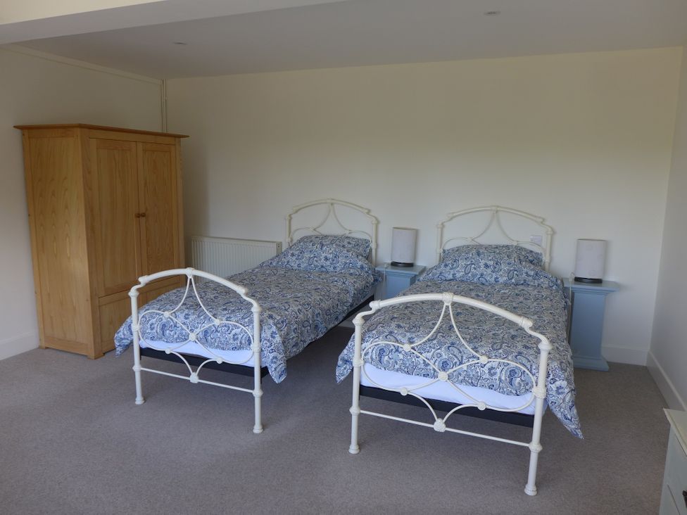 A bedroom with two single beds and a wardrobe at Little Evanses Dalwood near Axminster