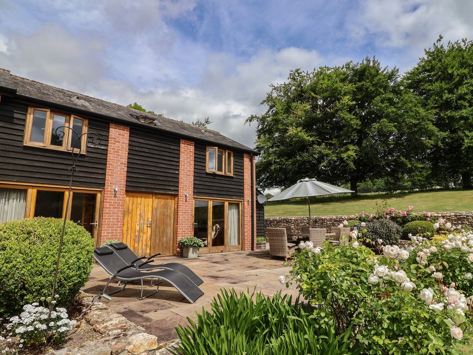 An outdoor area with a building and seating at The Old Log Shed in Honiton