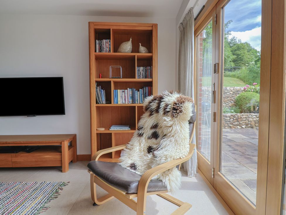 A living room with a chair and bookcase at The Old Log Shed in Honiton