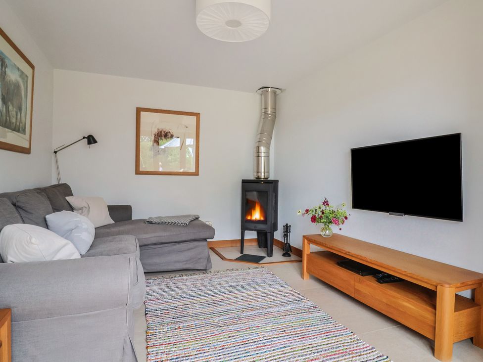 A living room with a sofa and a stove at The Old Log Shed in Honiton