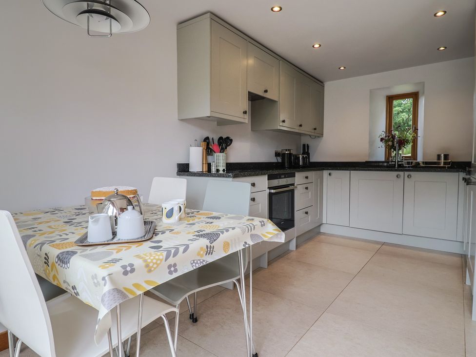 A kitchen with a table and chairs at The Old Log Shed in Honiton