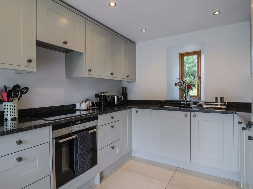 A kitchen with cabinets, countertop, and a window at The Old Log Shed in Honiton