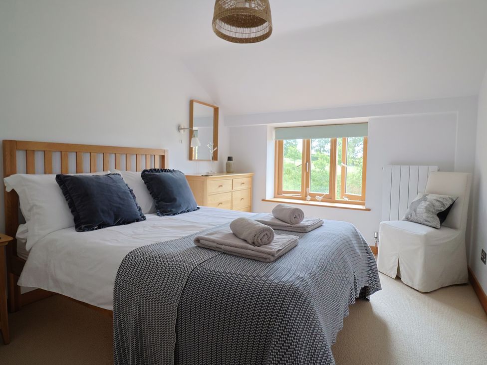 A bedroom with a bed and dresser at The Old Log Shed in Honiton