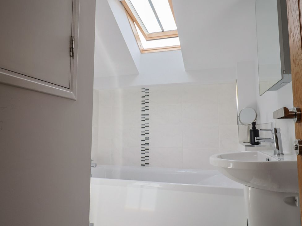 A bathroom with a bathtub and sink at The Old Log Shed in Honiton