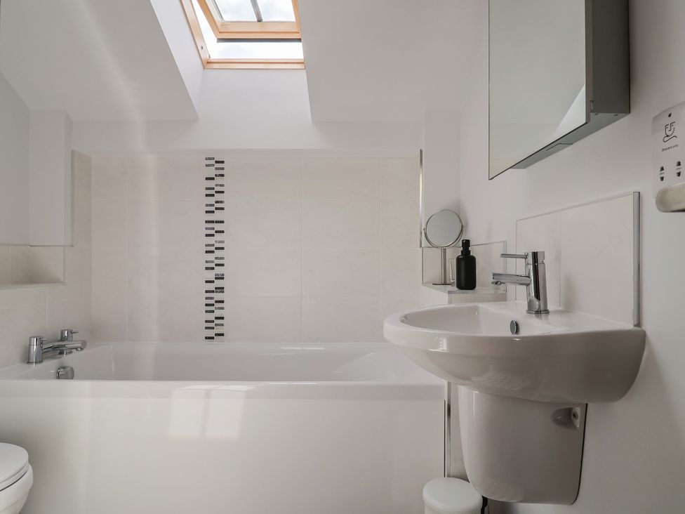A bathroom with a bathtub, toilet, and sink at The Old Log Shed in Honiton