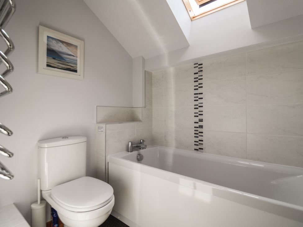 A bathroom with a bathtub and toilet at The Old Log Shed in Honiton