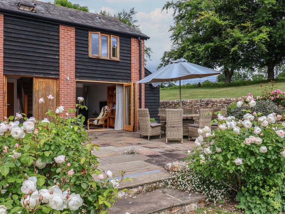 A patio with table and chairs at The Old Log Shed in Honiton