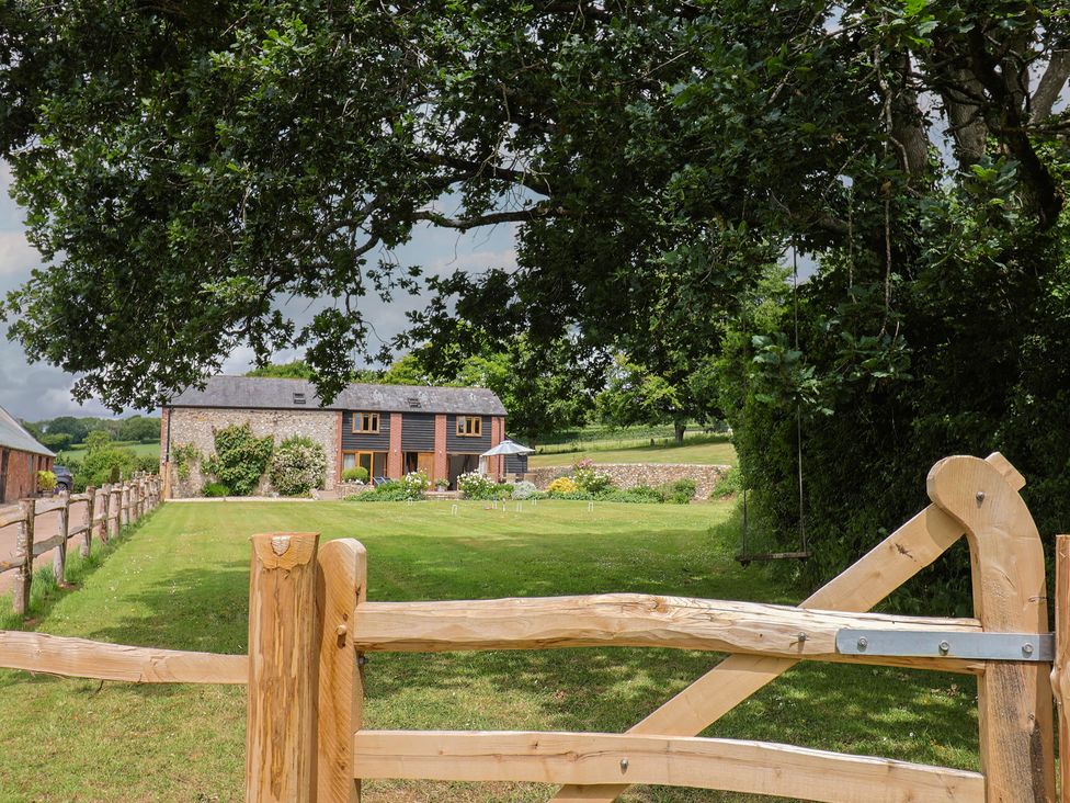 An outdoor area with a house in the background at The Old Log Shed in Honiton