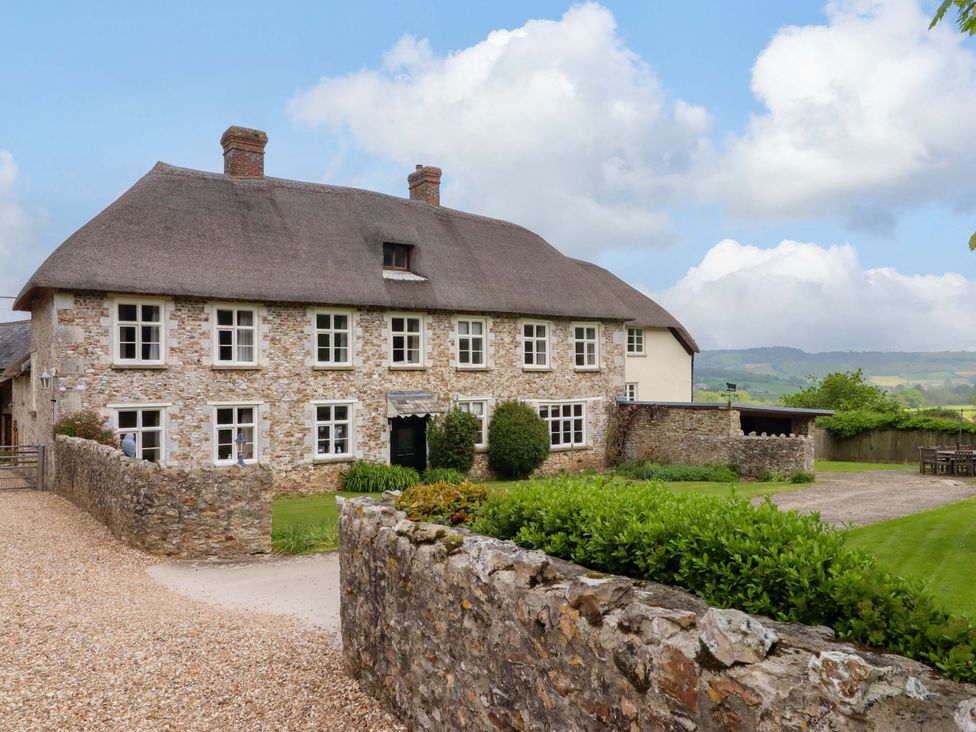 A stone house with a thatched roof and garden at Hornshayne Farmhouse in Farway, near Honiton