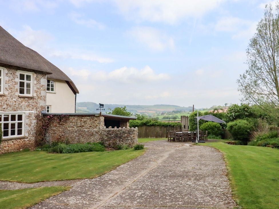 An outdoor area with a house, garden furniture, and a path at Hornshayne Farmhouse in Farway, near Honiton