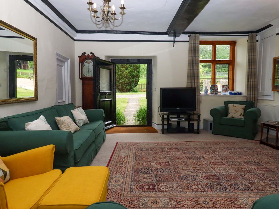 A living room with a television and mirror at Hornshayne Farmhouse, Farway, near Honiton