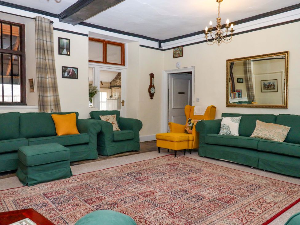 A living room with green sofas and a yellow armchair at Hornshayne Farmhouse Farway, near Honiton