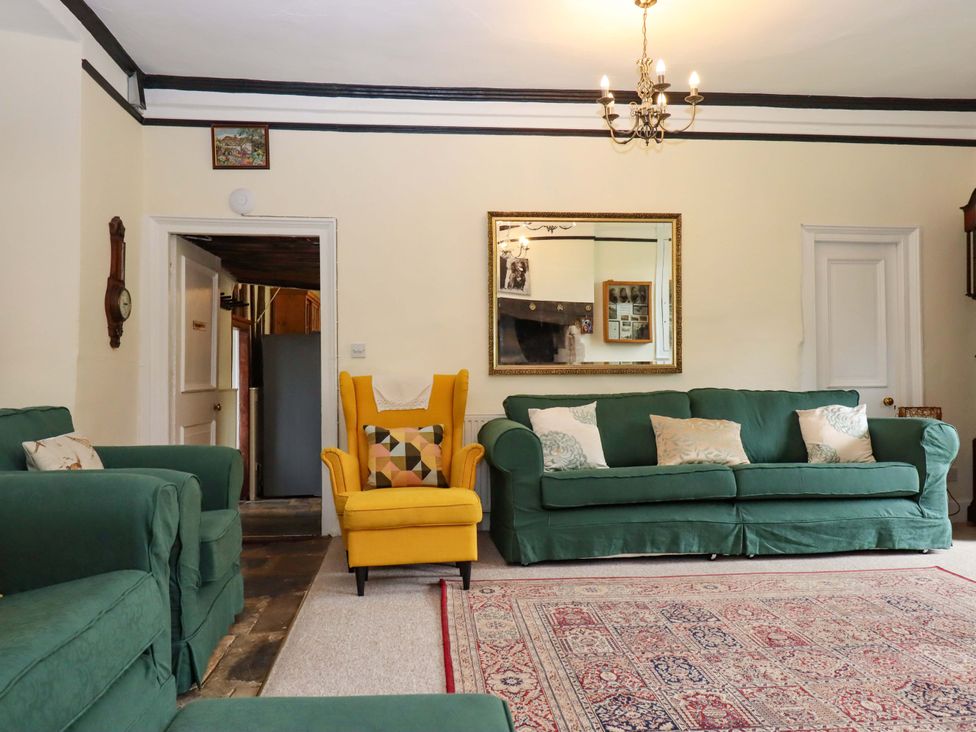 A living room with green sofas and a yellow armchair at Hornshayne Farmhouse in Farway, near Honiton