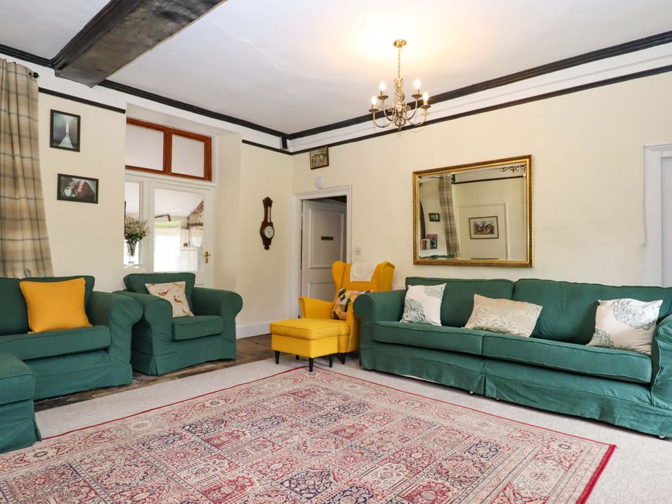 A living room with green sofas and an armchair at Hornshayne Farmhouse, Farway, near Honiton