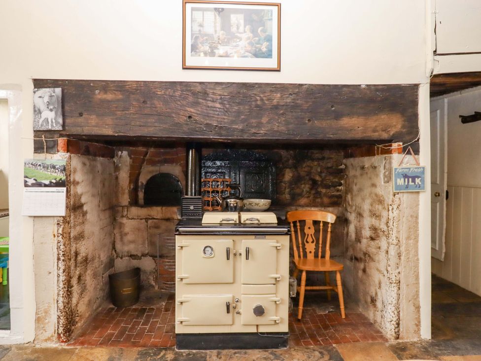 A kitchen with a range cooker and a stool at Hornshayne Farmhouse, Farway, near Honiton