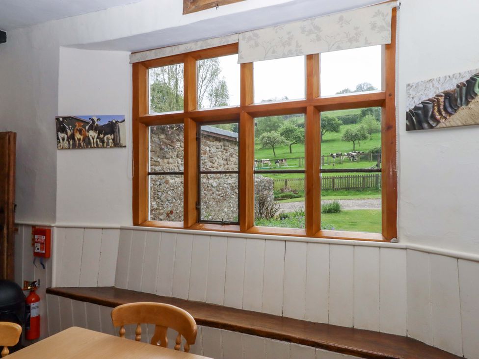 A dining room with a window and furnishings at Hornshayne Farmhouse Farway near Honiton