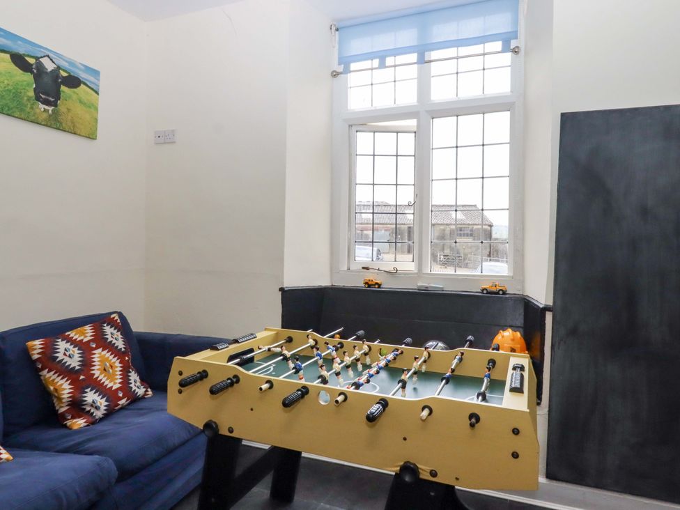 A foosball table and couch in a game room at Hornshayne Farmhouse near Honiton