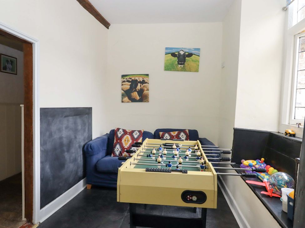 A foosball table and a sofa in a game room at Hornshayne Farmhouse, Farway, near Honiton