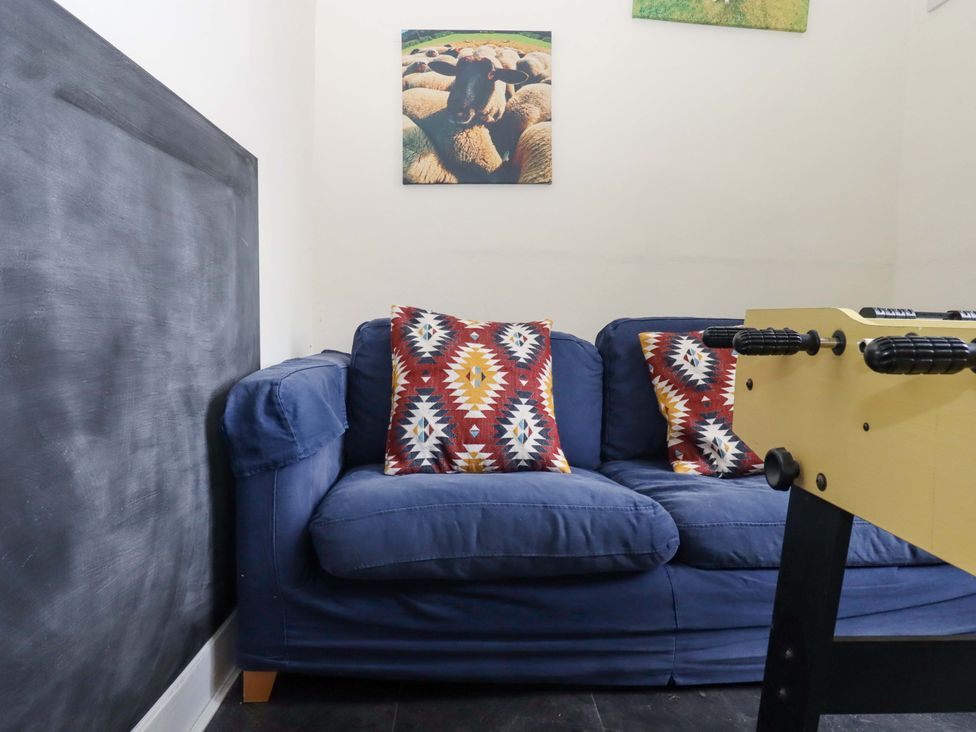 A sofa with cushions and a foosball table in the game room at Hornshayne Farmhouse, Farway, near Honiton
