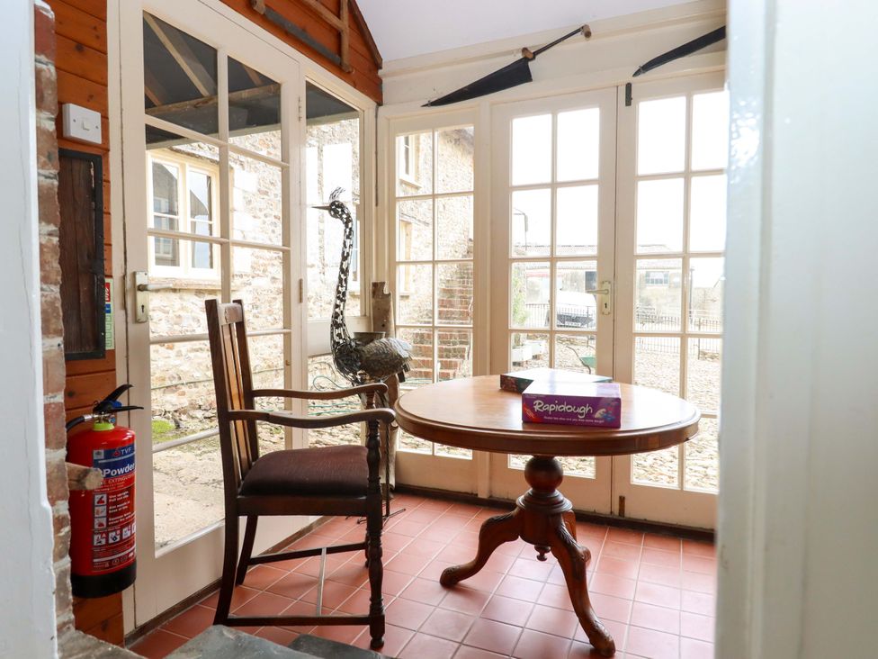 A conservatory with a table and a chair at Hornshayne Farmhouse, Farway, near Honiton