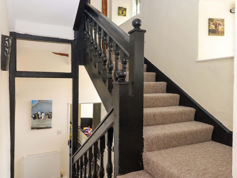 A staircase with a black handrail and carpet at Hornshayne Farmhouse Farway, near Honiton