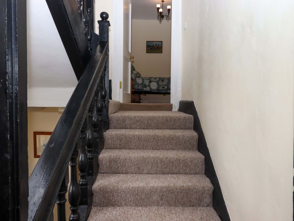 A staircase leading up to a hallway with a couch and a painting at Hornshayne Farmhouse near Honiton