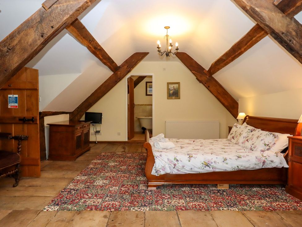 A bedroom with a bed and wooden beams at Hornshayne Farmhouse near Honiton