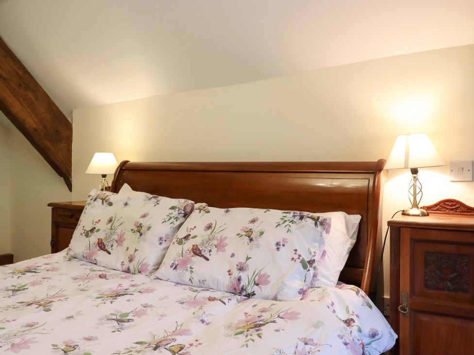A bedroom with a wooden bed and bedside lamps at Hornshayne Farmhouse, Farway, near Honiton