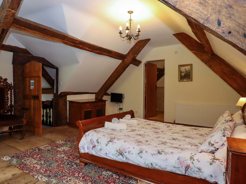 A bedroom with a bed, rug, and wooden beams at Hornshayne Farmhouse, Farway, near Honiton