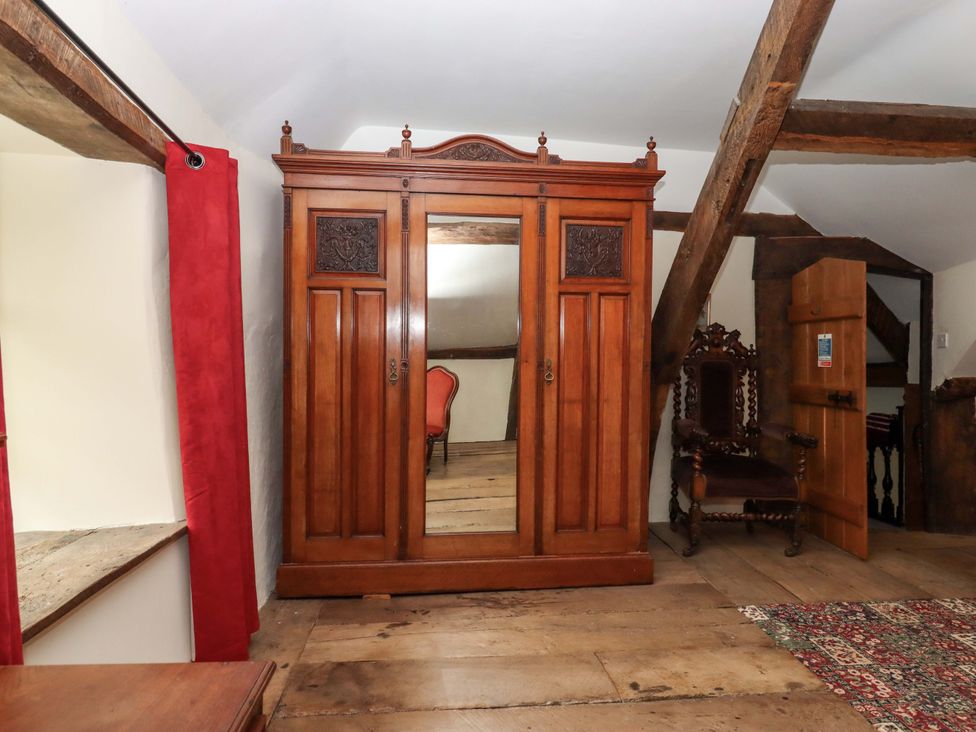 A bedroom with wardrobe and chair at Hornshayne Farmhouse, Farway, near Honiton