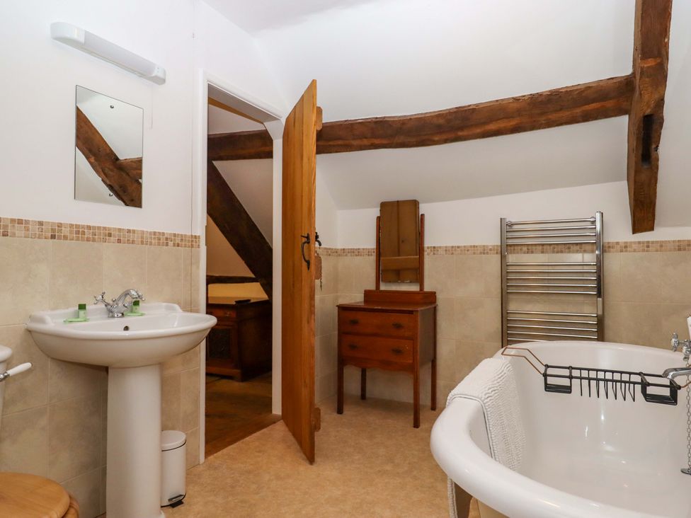 A bathroom with a bath, sink, and towels at Hornshayne Farmhouse in Farway, near Honiton