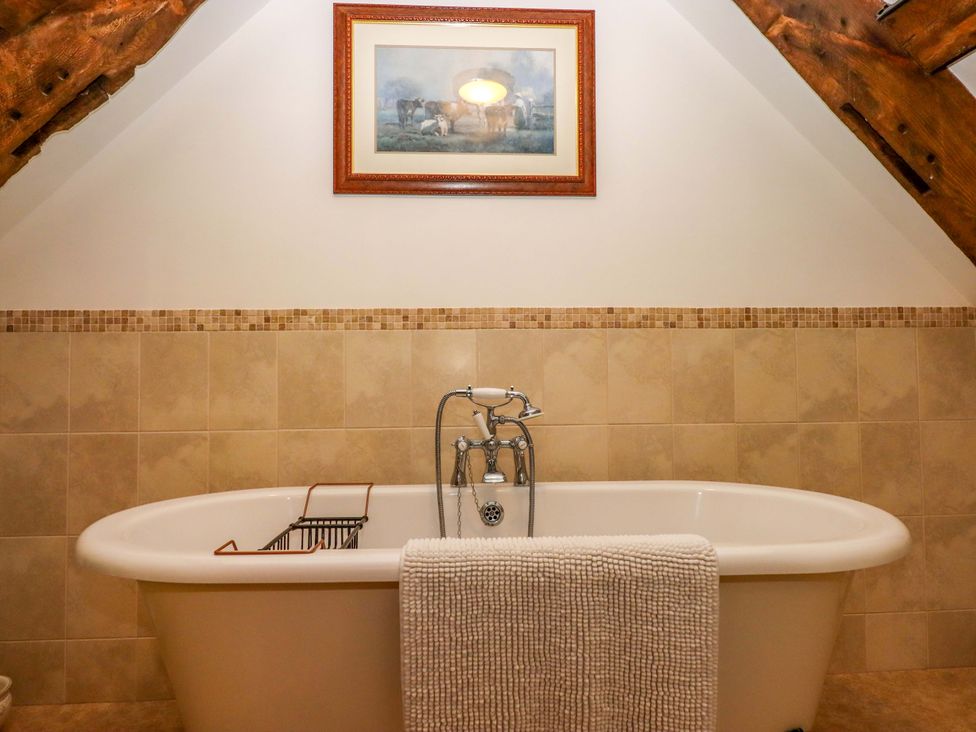 A bathroom with a bathtub and wall art at Hornshayne Farmhouse Farway, near Honiton