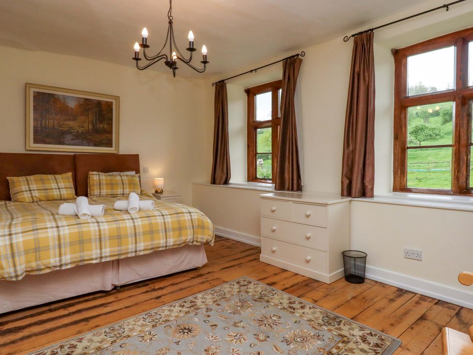 A bedroom with a bed and windows at Hornshayne Farmhouse, Farway, near Honiton