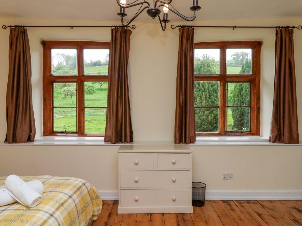 A bedroom with a bed and windows at Hornshayne Farmhouse, Farway, near Honiton