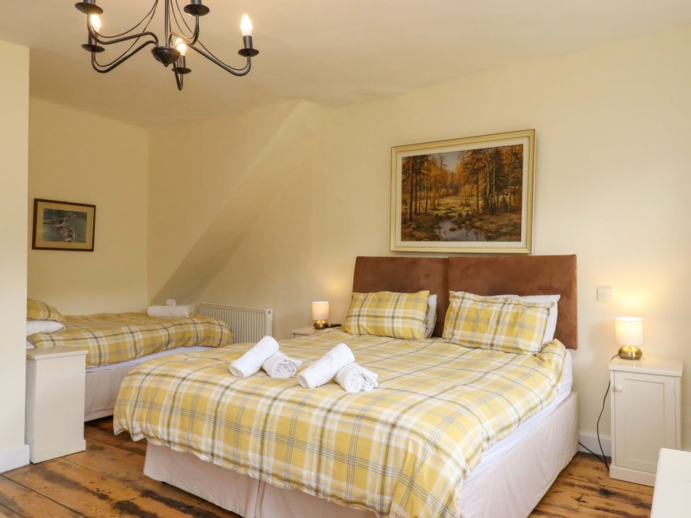 A bedroom with two beds and a chandelier at Hornshayne Farmhouse in Farway, near Honiton