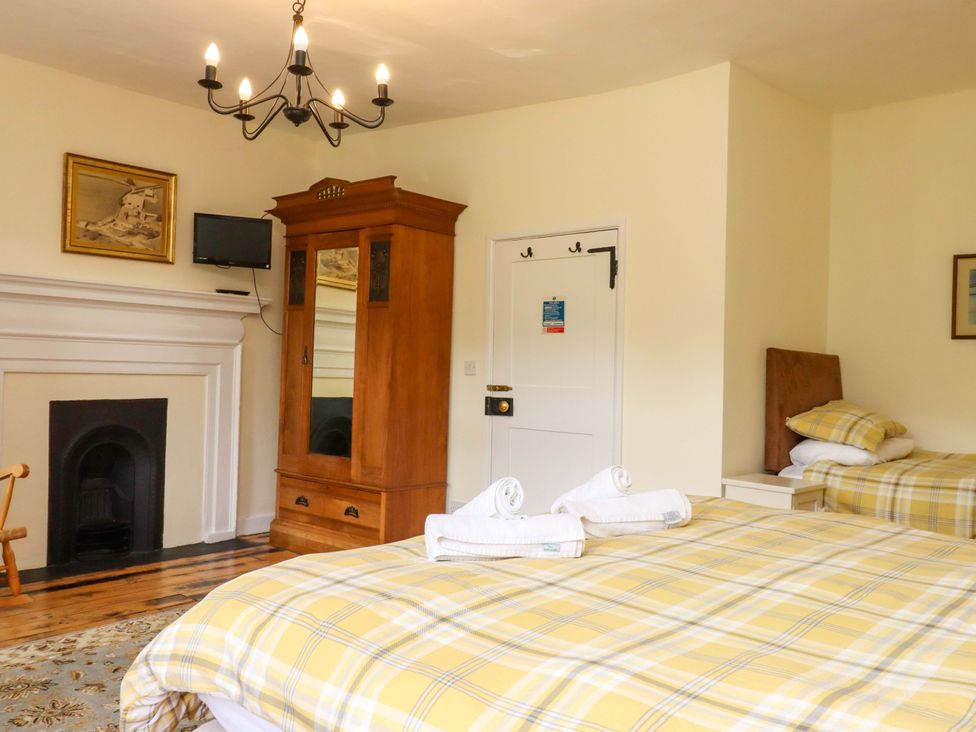 A bedroom with two beds and a wardrobe at Hornshayne Farmhouse Farway, near Honiton