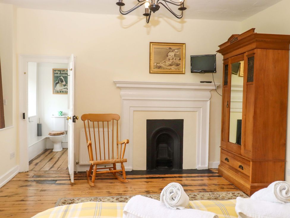 A bedroom with a rocking chair and wardrobe at Hornshayne Farmhouse in Farway, near Honiton