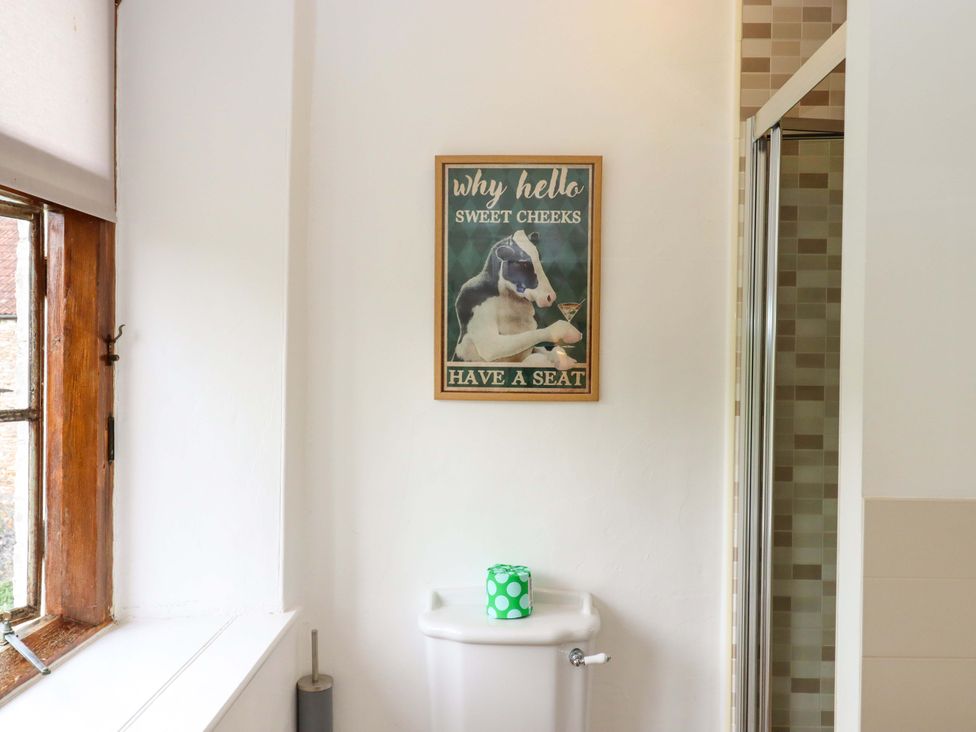 A bathroom with a poster on the wall at Hornshayne Farmhouse, Farway, near Honiton