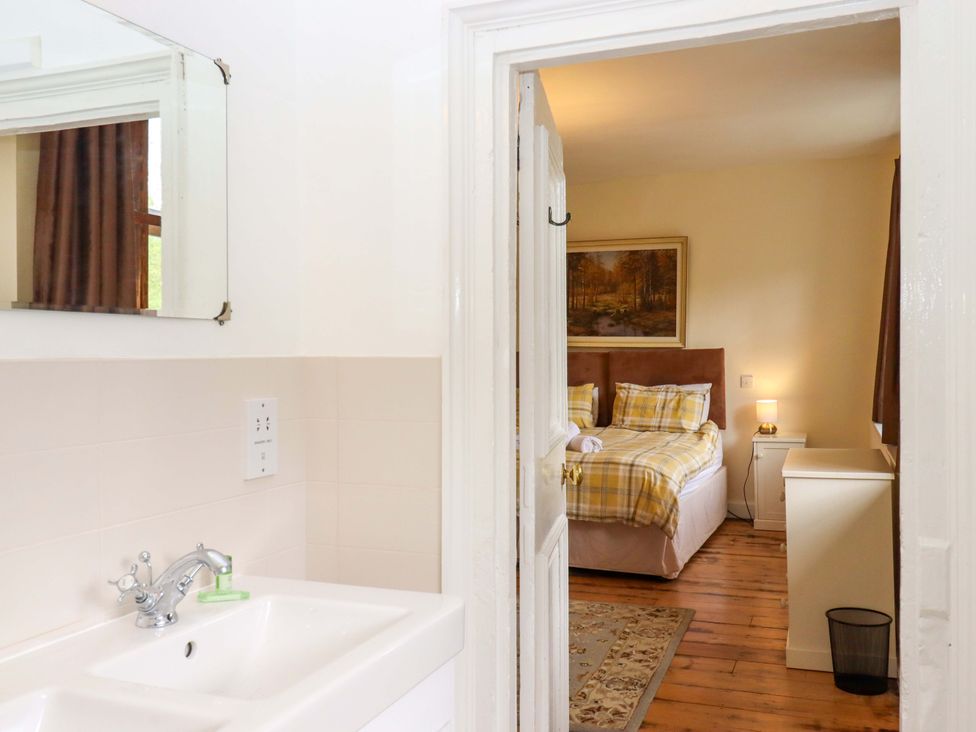 A bathroom with sink and mirror leading to a bedroom at Hornshayne Farmhouse in Farway, near Honiton
