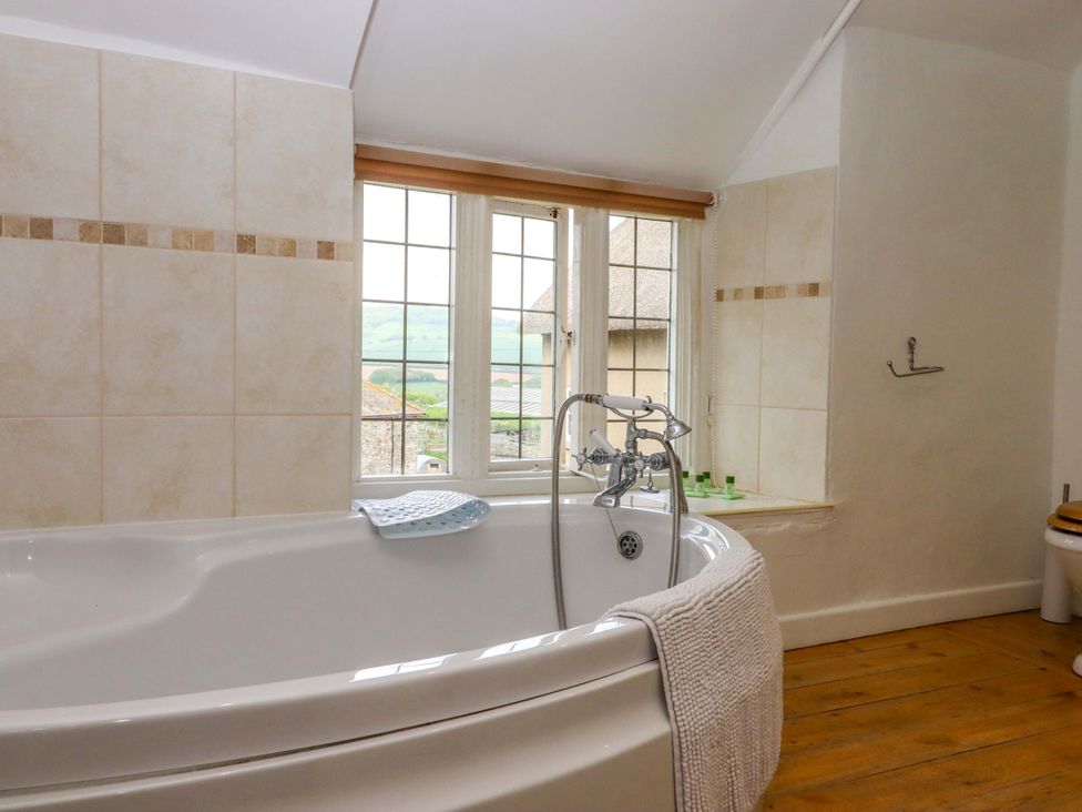 A bathroom with a bathtub and window at Hornshayne Farmhouse, Farway, near Honiton