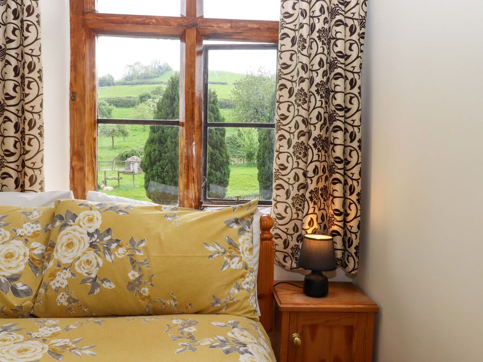 A bedroom with a bed and a window overlooking green fields at Hornshayne Farmhouse, Farway, near Honiton