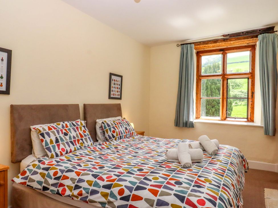 A bedroom with a bed and window at Hornshayne Farmhouse near Honiton